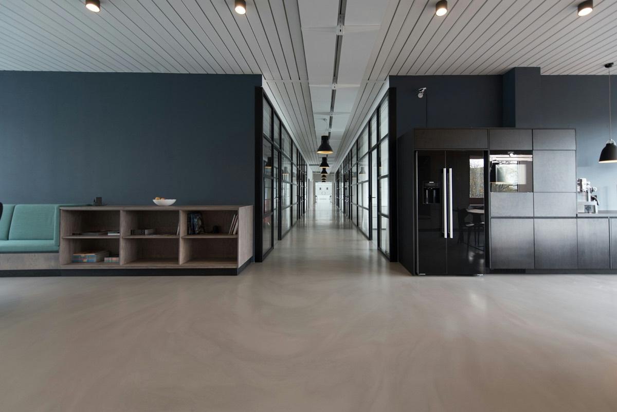Modern commercial office interior with glazed partitions and concrete floor
